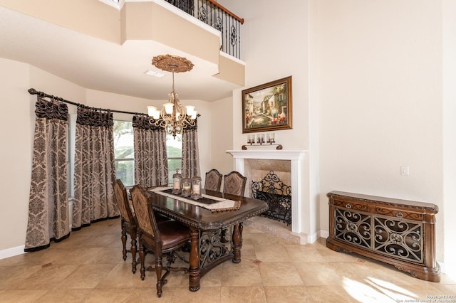 dining space with a tile fireplace, a towering ceiling, and a chandelier