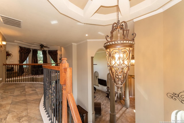 hallway with ornamental molding and a chandelier