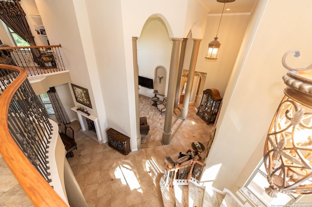 interior space featuring decorative columns, crown molding, and a towering ceiling