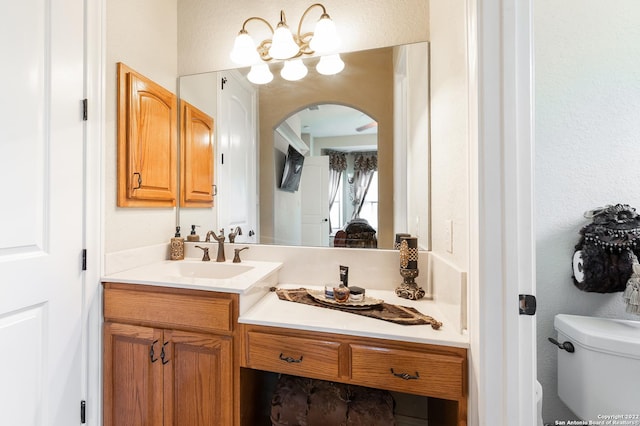 bathroom with vanity, toilet, and an inviting chandelier