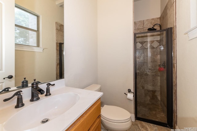 bathroom featuring vanity, a shower with shower door, and toilet