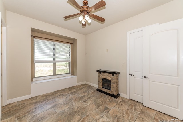 unfurnished living room featuring ceiling fan and a fireplace