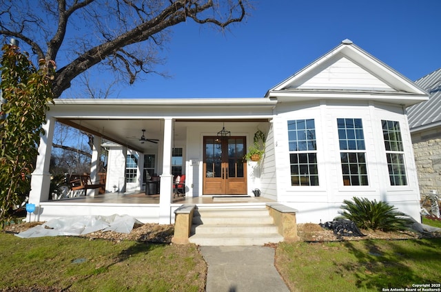 doorway to property featuring french doors, a porch, and a lawn