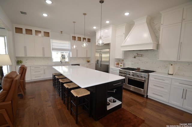 kitchen with white cabinets, custom range hood, high quality appliances, and a kitchen island