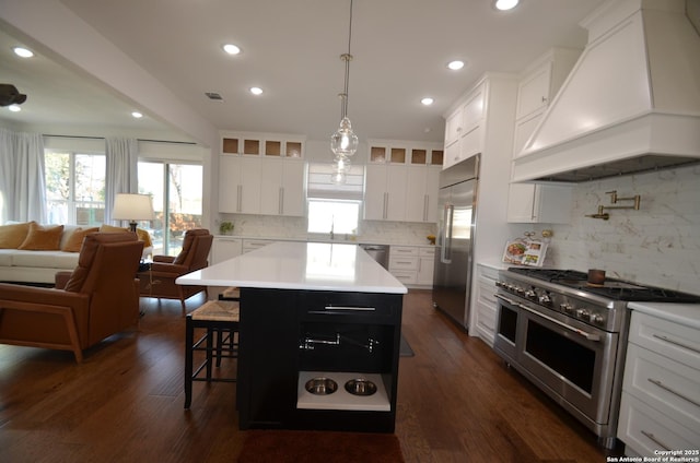 kitchen with dark wood-type flooring, premium appliances, white cabinets, a kitchen island, and custom exhaust hood