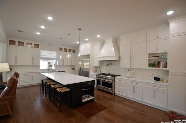 kitchen featuring premium range hood, a kitchen island, white cabinetry, a breakfast bar area, and high end appliances