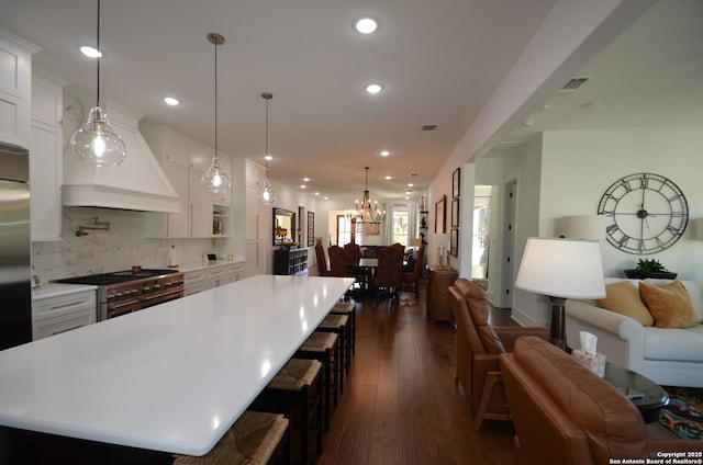 kitchen featuring white cabinets, custom exhaust hood, stainless steel appliances, and a spacious island