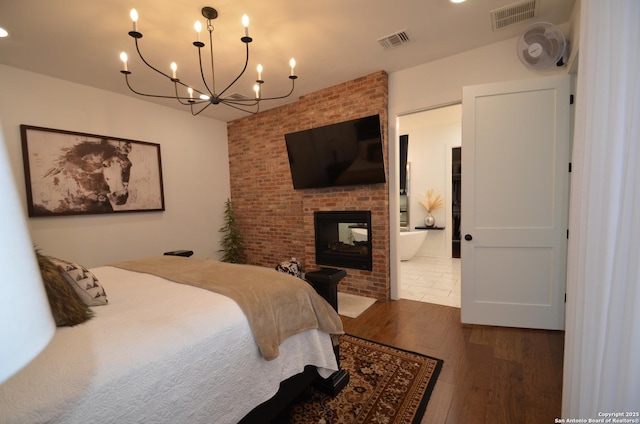 bedroom with dark wood-type flooring, connected bathroom, and a brick fireplace