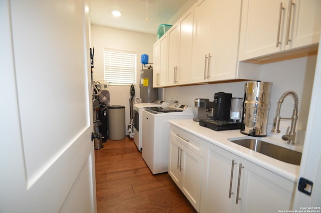 clothes washing area featuring electric water heater, dark hardwood / wood-style flooring, sink, and washer and dryer