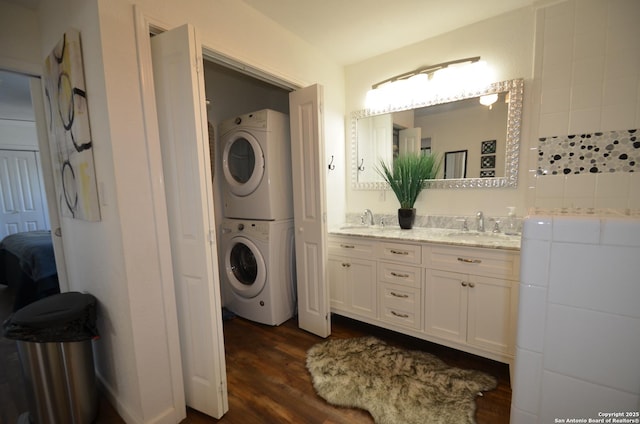 laundry room with dark wood-type flooring, stacked washer / drying machine, and sink