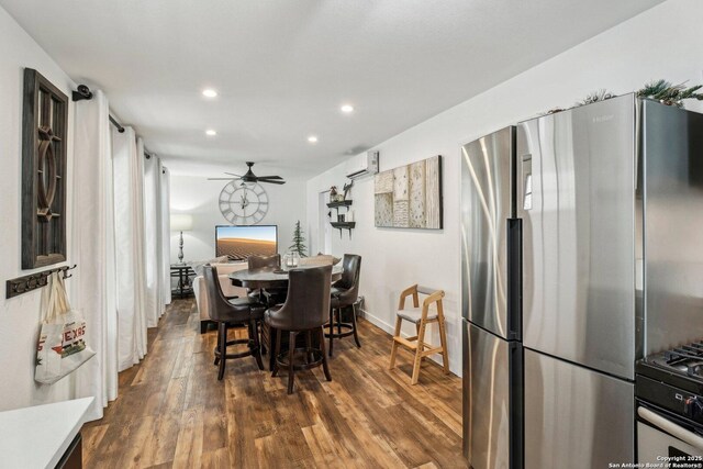 dining room with dark wood-type flooring, ceiling fan, and a wall unit AC