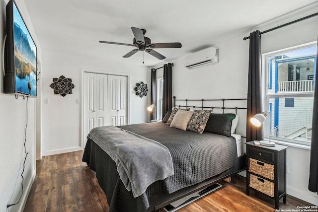 bedroom with dark wood-type flooring, a closet, ceiling fan, and a wall unit AC