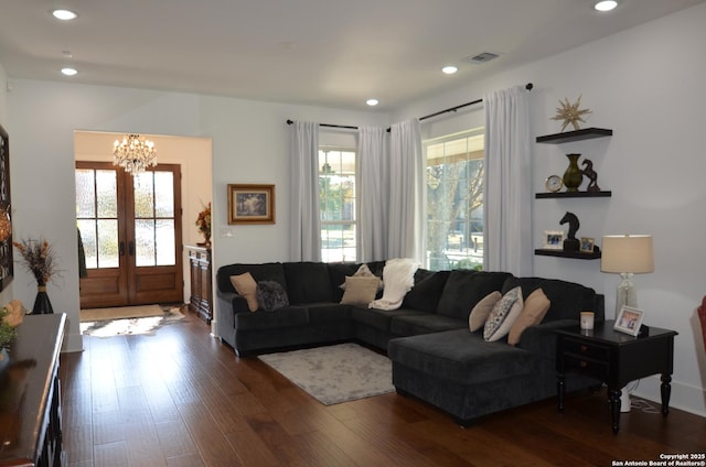 living room with a wealth of natural light, dark hardwood / wood-style flooring, and french doors