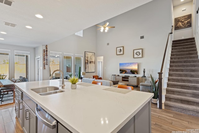 kitchen featuring dishwasher, sink, a center island with sink, and light wood-type flooring