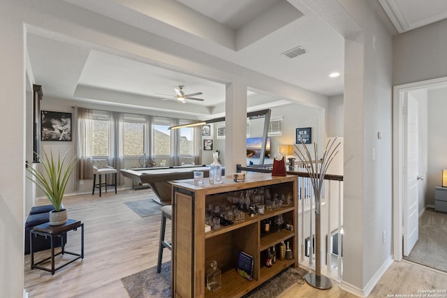 kitchen featuring ceiling fan, a tray ceiling, and light hardwood / wood-style flooring