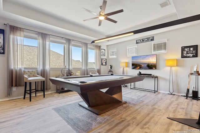 game room featuring a raised ceiling, plenty of natural light, and light hardwood / wood-style floors