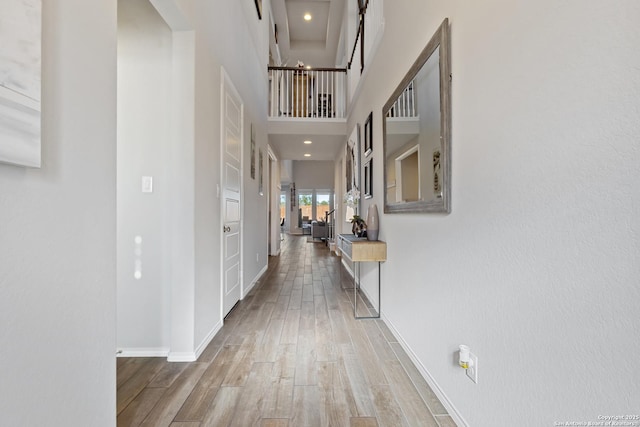 hall featuring hardwood / wood-style flooring and a towering ceiling