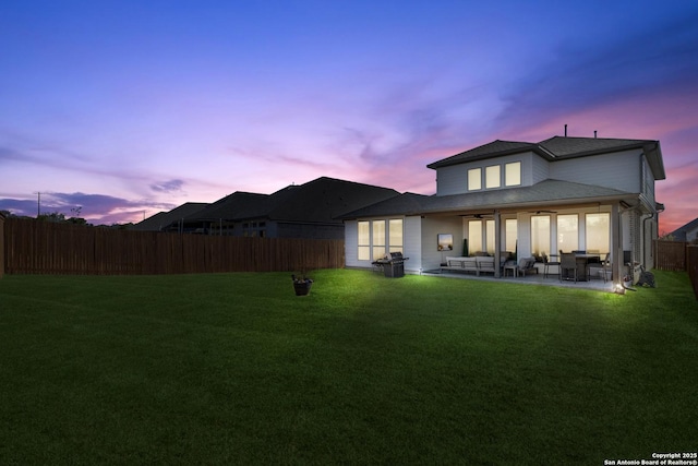 back house at dusk featuring an outdoor hangout area, a yard, and a patio area