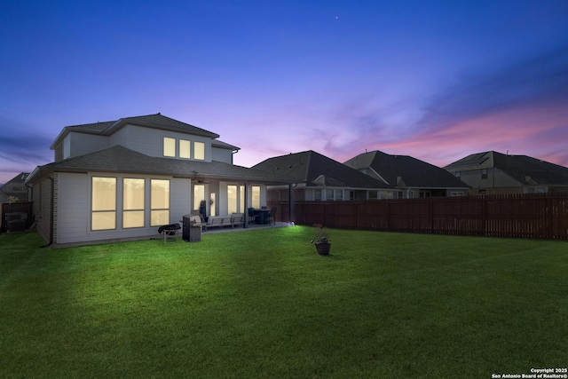 back house at dusk with a yard and a patio area