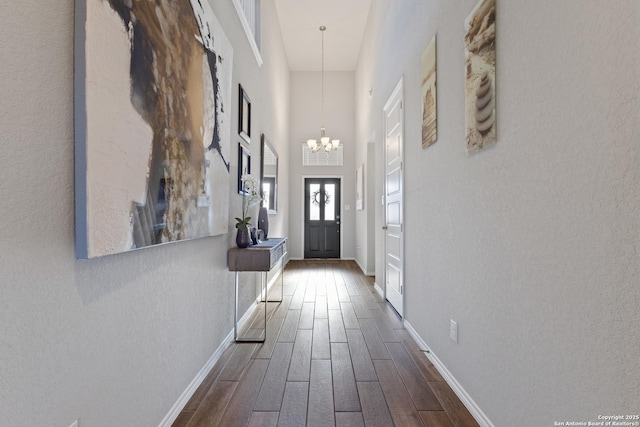 corridor featuring an inviting chandelier, dark hardwood / wood-style floors, and a high ceiling