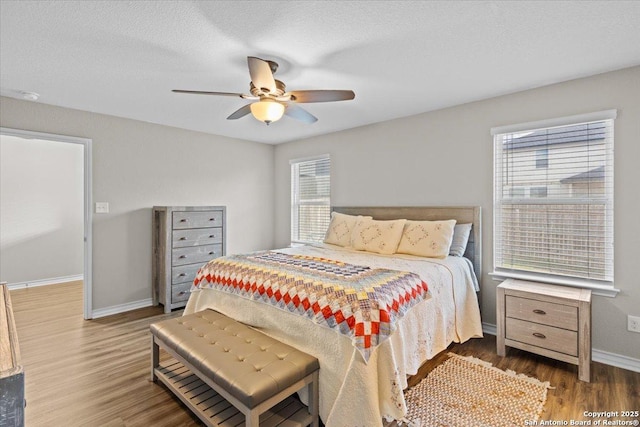 bedroom with ceiling fan, wood-type flooring, multiple windows, and a textured ceiling