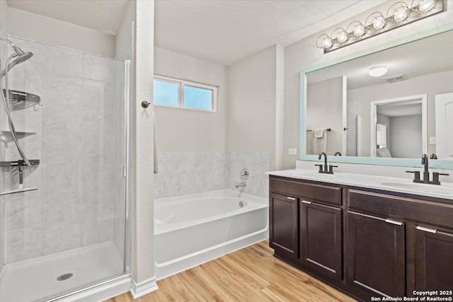 bathroom featuring vanity, hardwood / wood-style flooring, plus walk in shower, and a textured ceiling