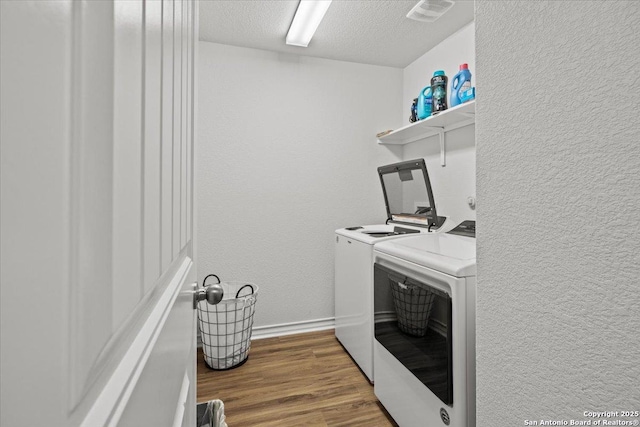 washroom with separate washer and dryer, hardwood / wood-style floors, and a textured ceiling