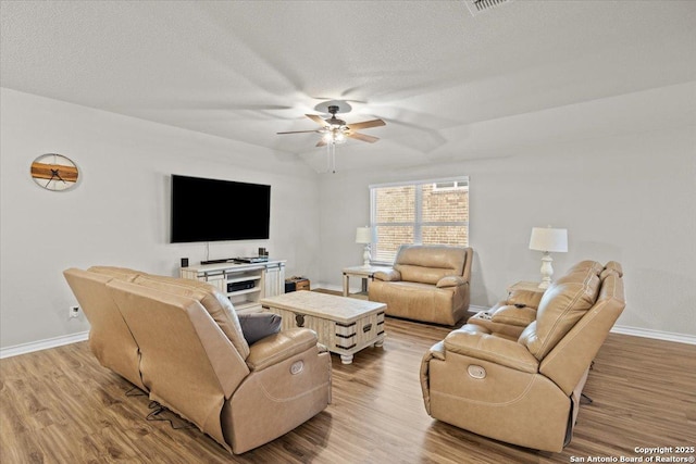 living room featuring vaulted ceiling, a textured ceiling, ceiling fan, and light hardwood / wood-style flooring