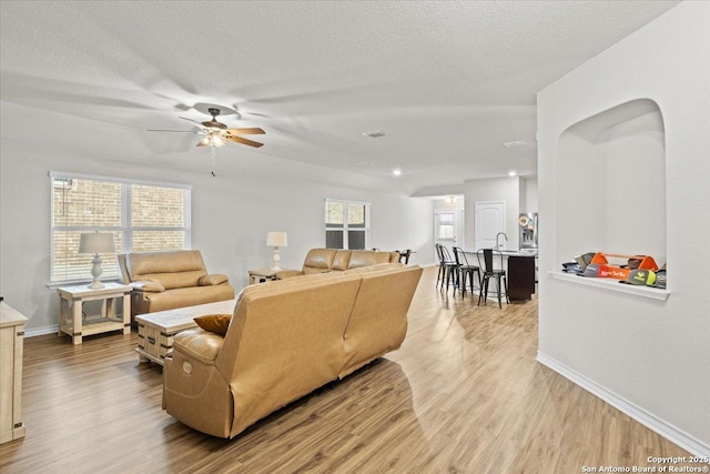 living room with ceiling fan, plenty of natural light, hardwood / wood-style floors, and a textured ceiling