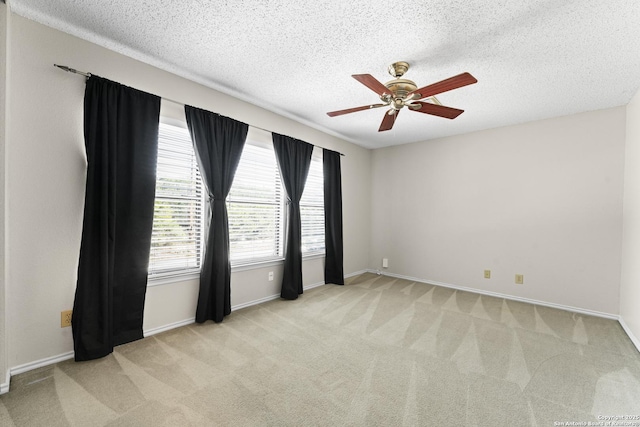 spare room featuring ceiling fan, light carpet, and a textured ceiling