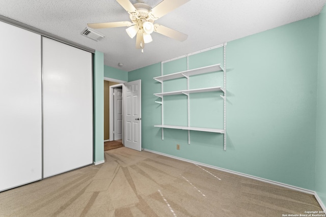 unfurnished bedroom featuring ceiling fan, carpet floors, a textured ceiling, and a closet