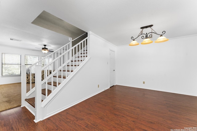 stairs with wood-type flooring, ornamental molding, and ceiling fan with notable chandelier