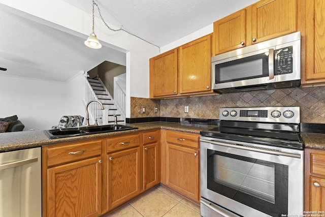 kitchen featuring sink, tasteful backsplash, decorative light fixtures, light tile patterned floors, and stainless steel appliances