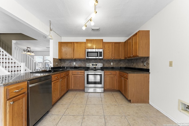 kitchen featuring light tile patterned flooring, sink, backsplash, kitchen peninsula, and stainless steel appliances