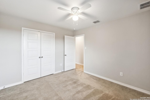 unfurnished bedroom with light carpet, ceiling fan, and a closet