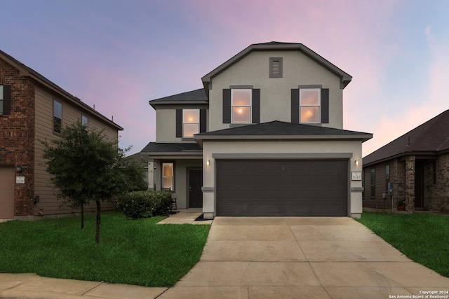 view of property featuring a garage and a lawn