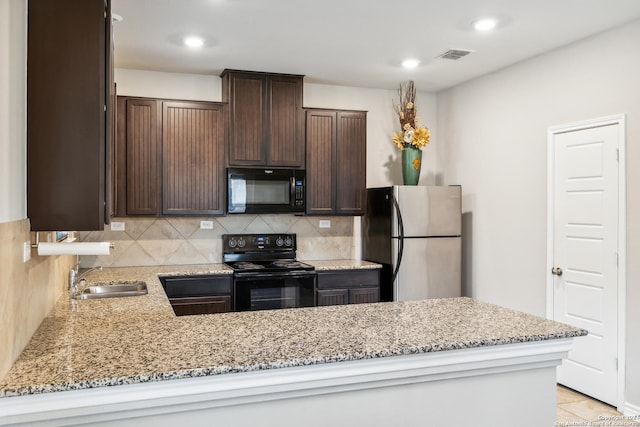 kitchen with sink, kitchen peninsula, light stone counters, and black appliances