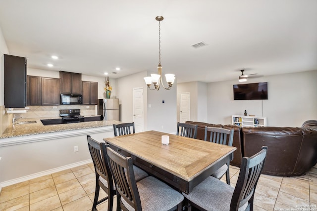 tiled dining room featuring sink and ceiling fan with notable chandelier