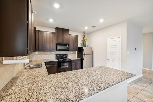 kitchen featuring sink, light stone counters, kitchen peninsula, decorative backsplash, and black appliances