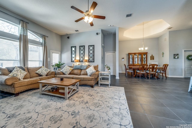 living room with ceiling fan with notable chandelier and dark tile patterned floors