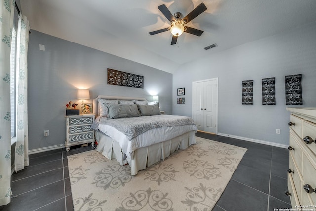 bedroom featuring lofted ceiling, dark tile patterned flooring, a closet, and ceiling fan