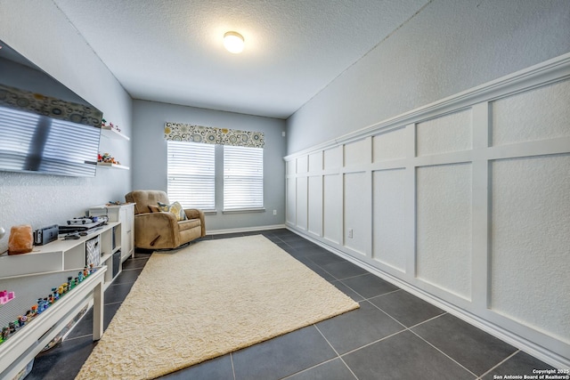 living area featuring a textured ceiling and dark tile patterned floors