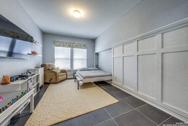 bedroom featuring a textured ceiling and dark tile patterned floors