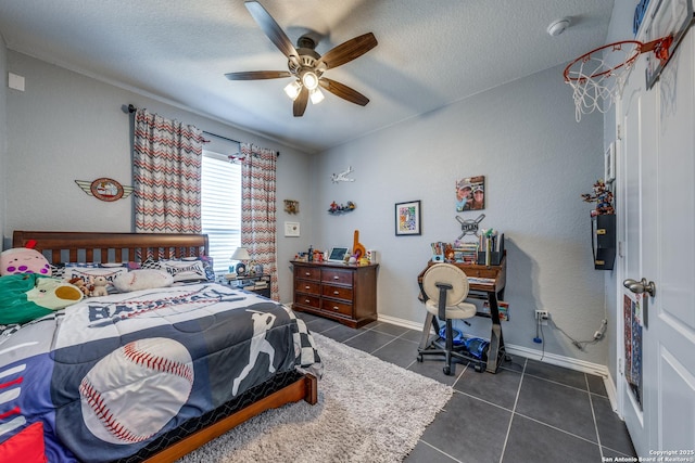 bedroom featuring ceiling fan, a textured ceiling, and dark tile patterned floors