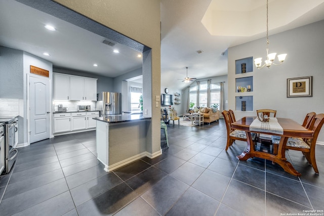 kitchen with dark tile patterned flooring, white cabinets, stainless steel fridge with ice dispenser, decorative backsplash, and decorative light fixtures