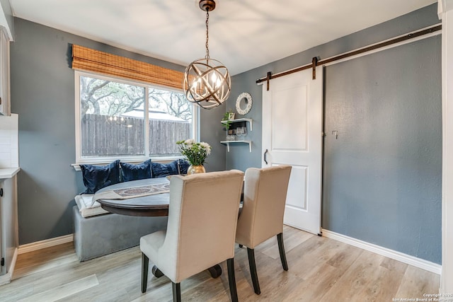 dining room featuring breakfast area, a barn door, and light wood-type flooring