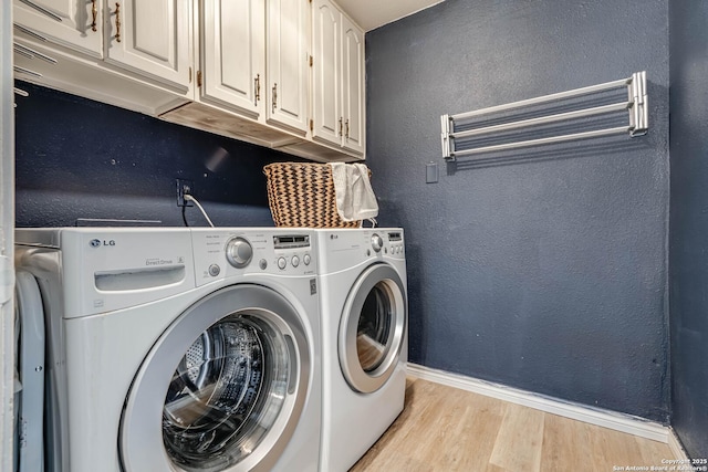 laundry room featuring cabinets, washer and clothes dryer, and light hardwood / wood-style flooring