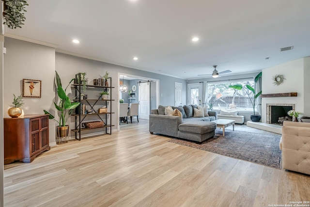 living room featuring crown molding, a barn door, ceiling fan, and light hardwood / wood-style floors