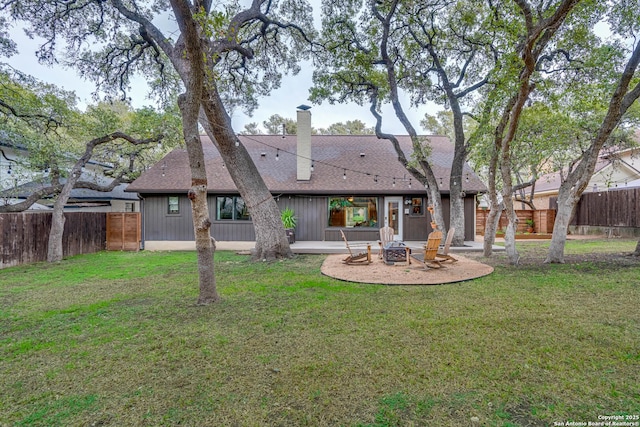 back of property with a patio area, a fire pit, and a lawn