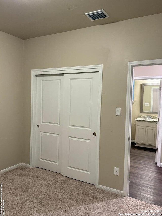 unfurnished bedroom with sink, carpet floors, and a closet